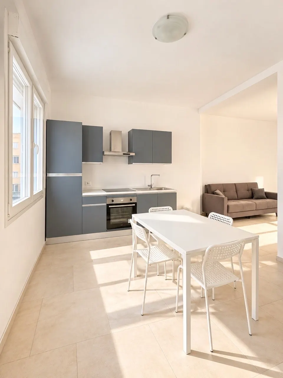 Appartamento G – Bilocale: Zona giorno e cucina – Spazio con cucina, tavolo con sedie e divano.